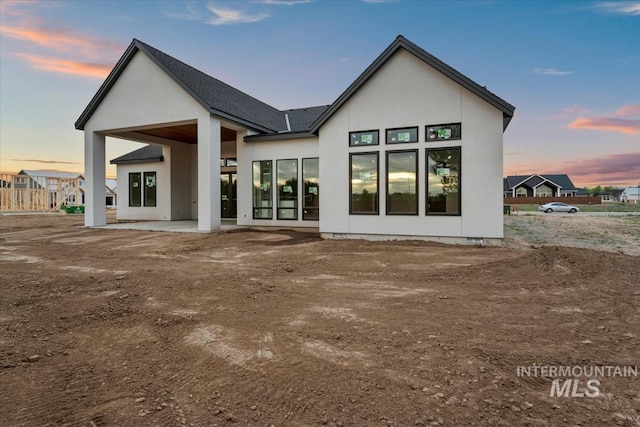 rear view of property featuring a patio and stucco siding