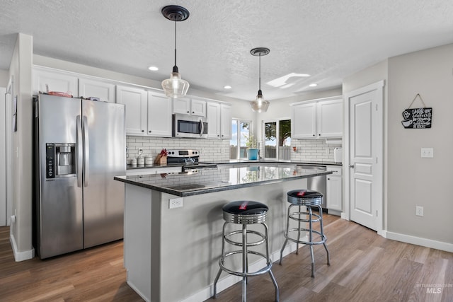 2145 W Quilceda, Kuna, ID 83634 - kitchen featuring stainless steel appliances, white cabinets, wood finished floors, decorative backsplash, and a textured ceiling