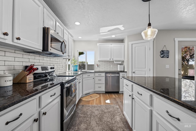 2145 W Quilceda, Kuna, ID 83634 - kitchen with stainless steel appliances, white cabinetry, a textured ceiling, light wood-type flooring, and tasteful backsplash