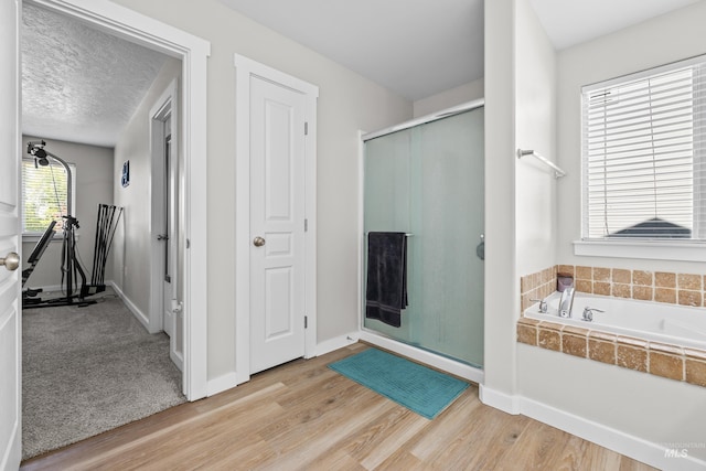 2145 W Quilceda, Kuna, ID 83634 - bathroom with a shower stall, a bath, wood finished floors, baseboards, and a textured ceiling
