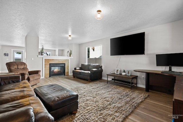 2145 W Quilceda, Kuna, ID 83634 - living area with wood finished floors, a textured ceiling, a tiled fireplace, and baseboards