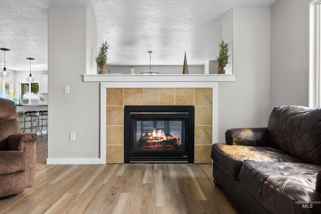2145 W Quilceda, Kuna, ID 83634 - living room featuring a fireplace, wood finished floors, a textured ceiling, and baseboards