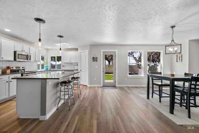 2145 W Quilceda, Kuna, ID 83634 - kitchen with stainless steel appliances, light wood-style flooring, a kitchen island, a breakfast bar, and a textured ceiling