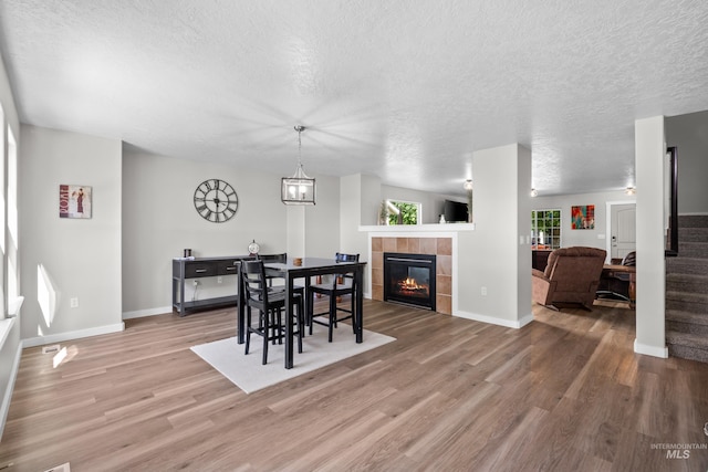 2145 W Quilceda, Kuna, ID 83634 - dining space featuring a textured ceiling, wood finished floors, a tile fireplace, and baseboards