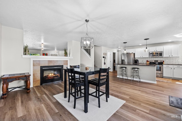 2145 W Quilceda, Kuna, ID 83634 - dining area featuring light wood-type flooring, a fireplace, a chandelier, and a textured ceiling