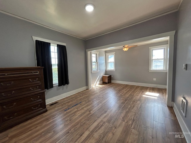 unfurnished bedroom with hardwood / wood-style floors, ornamental molding, and multiple windows