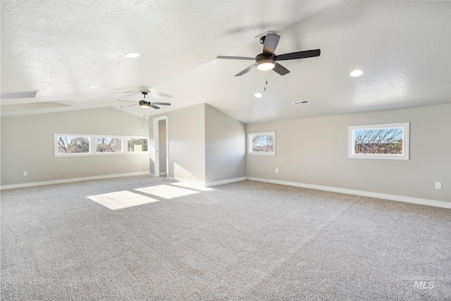 unfurnished room featuring lofted ceiling, a textured ceiling, ceiling fan, and a wealth of natural light