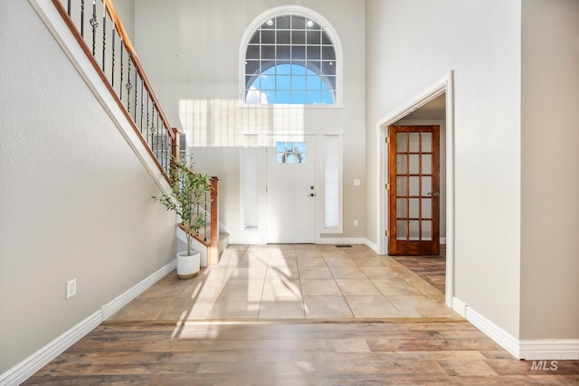 foyer entrance with light hardwood / wood-style flooring and a towering ceiling