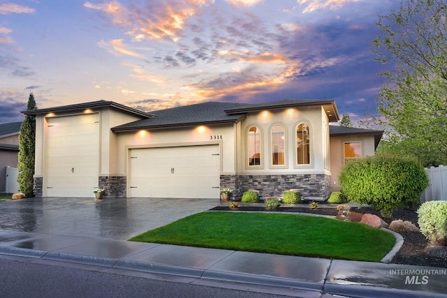 view of front facade featuring stone siding, a garage, stucco siding, and concrete driveway