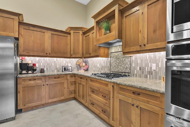 kitchen with appliances with stainless steel finishes, decorative backsplash, light stone countertops, and light marble finish flooring