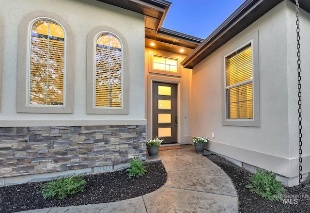 doorway to property with stucco siding and stone siding