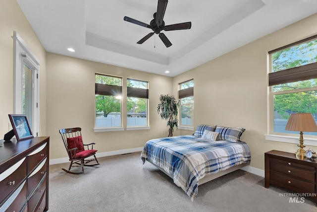 carpeted bedroom featuring baseboards, recessed lighting, a tray ceiling, and a ceiling fan