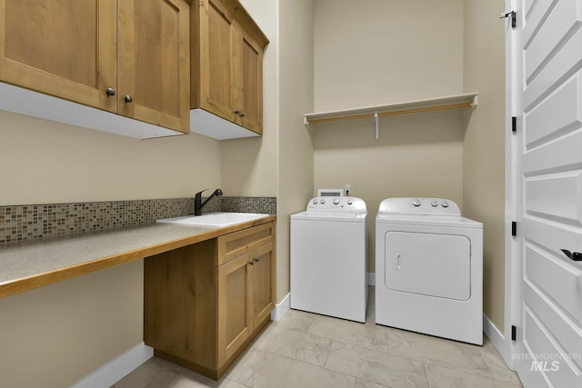 washroom with washing machine and dryer, cabinet space, and baseboards