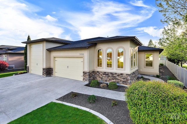 view of front of house featuring a garage, stucco siding, concrete driveway, stone siding, and fence