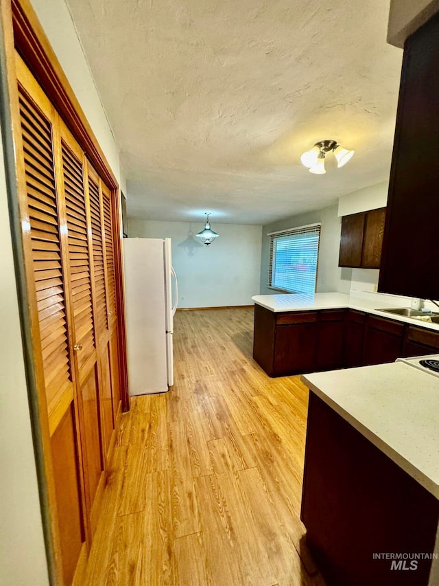 kitchen featuring white fridge, light hardwood / wood-style floors, a textured ceiling, and sink