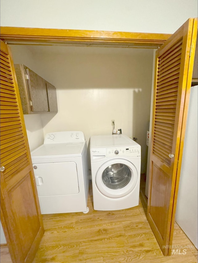 washroom featuring light hardwood / wood-style floors, cabinets, and washer and clothes dryer