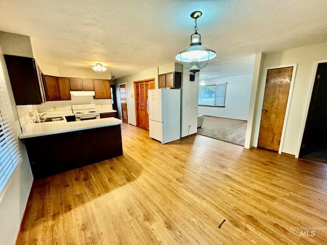 kitchen with light hardwood / wood-style flooring, kitchen peninsula, sink, pendant lighting, and white appliances