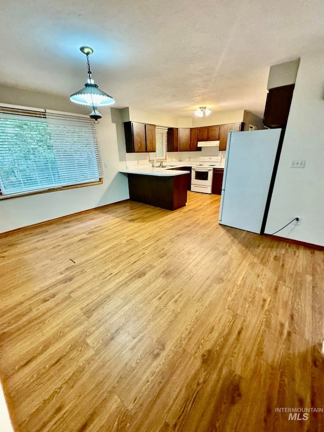 kitchen featuring light wood-type flooring, pendant lighting, and white appliances