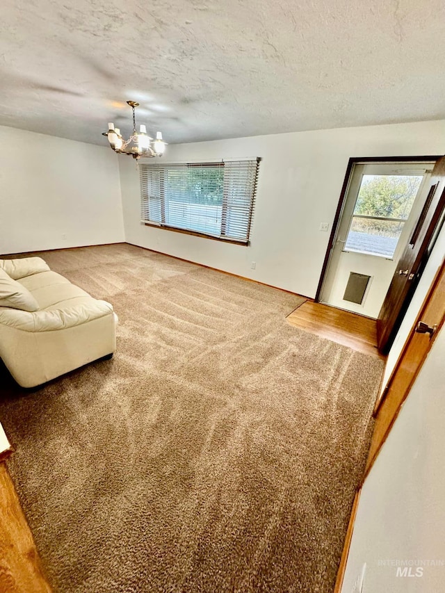 living room with a textured ceiling, a chandelier, and carpet flooring