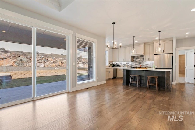 bar featuring a notable chandelier, stainless steel appliances, decorative backsplash, dark wood finished floors, and pendant lighting