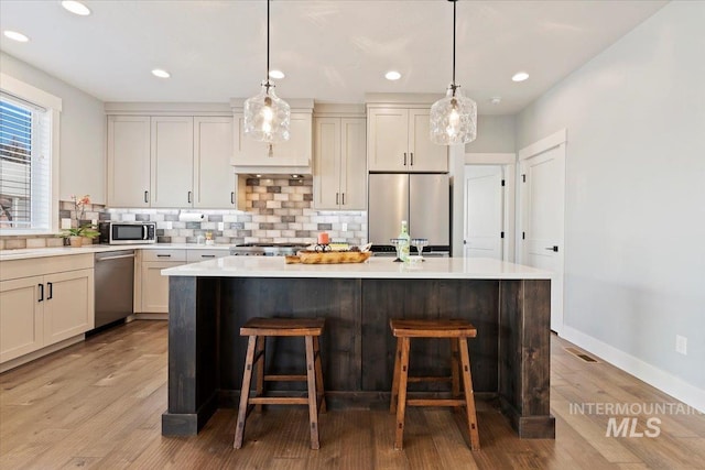 kitchen featuring tasteful backsplash, visible vents, a center island, stainless steel appliances, and a kitchen bar