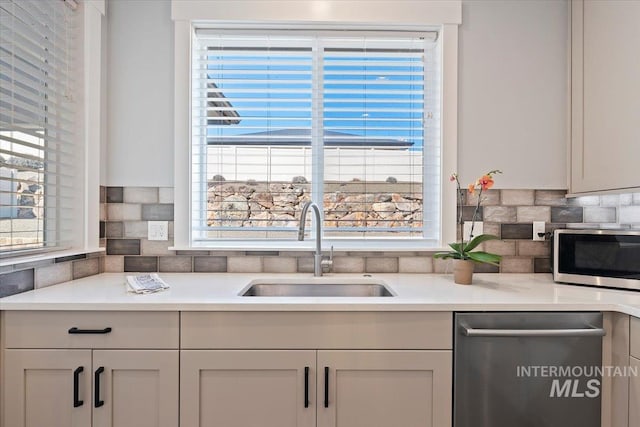 kitchen featuring a healthy amount of sunlight, backsplash, stainless steel appliances, and a sink