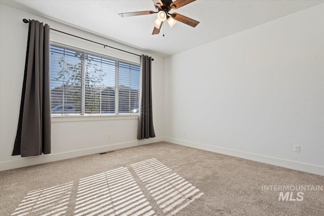 empty room featuring ceiling fan, carpet, visible vents, and baseboards