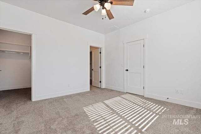 unfurnished bedroom featuring carpet floors, a spacious closet, baseboards, and a closet