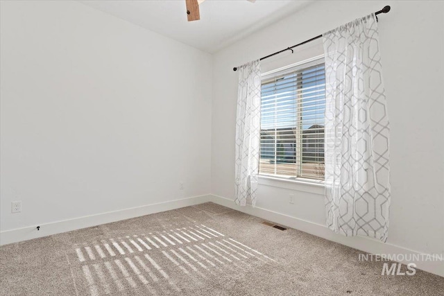 carpeted empty room featuring baseboards, visible vents, and ceiling fan