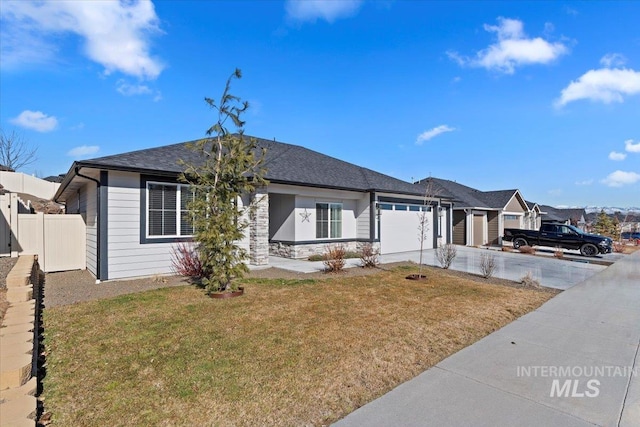 ranch-style home with driveway, a garage, stone siding, fence, and a front yard