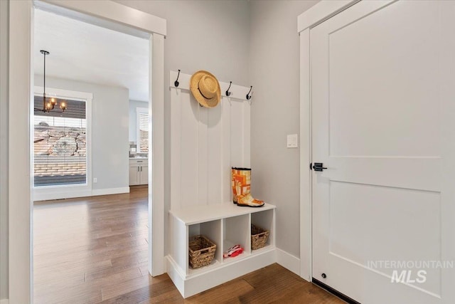 mudroom with a notable chandelier, dark wood-style flooring, and baseboards