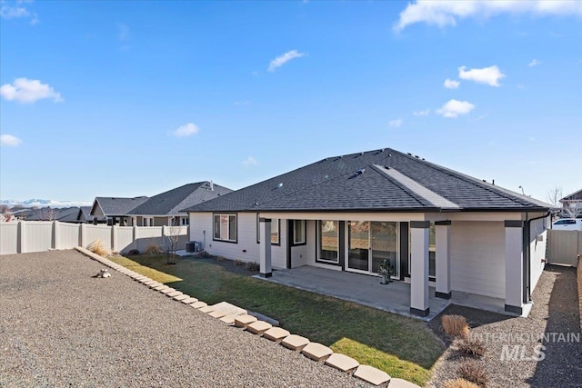 rear view of property with a shingled roof, central AC unit, a lawn, a patio, and a fenced backyard