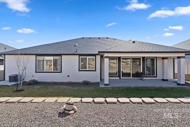 back of house with a patio area, a shingled roof, central AC, and a lawn