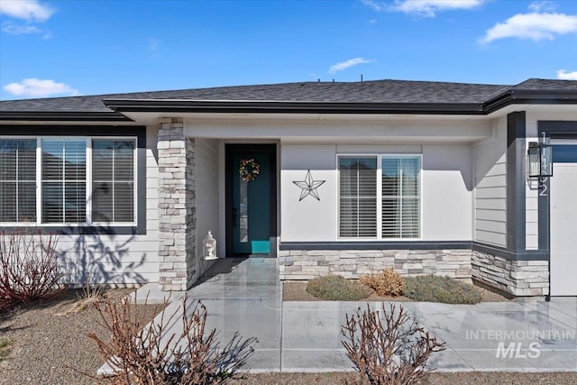 doorway to property featuring stone siding and a shingled roof