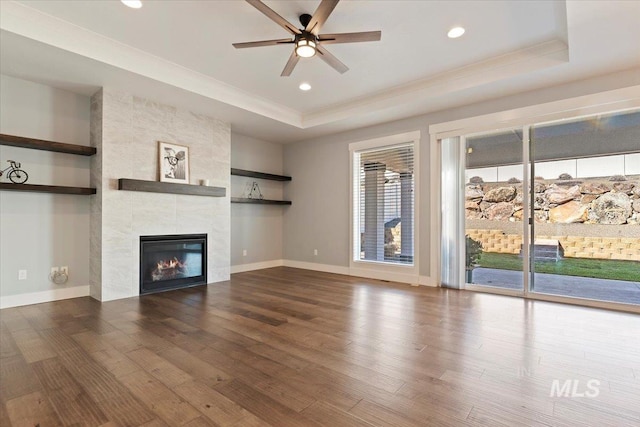 unfurnished living room featuring a fireplace, plenty of natural light, and a raised ceiling