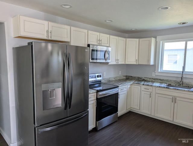 kitchen featuring a sink, stainless steel appliances, white cabinetry, dark wood-style flooring, and light stone countertops