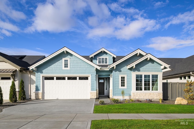 craftsman-style house featuring fence, driveway, and stone siding