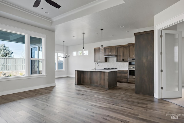 kitchen with under cabinet range hood, light countertops, wood finished floors, dark brown cabinetry, and ceiling fan with notable chandelier