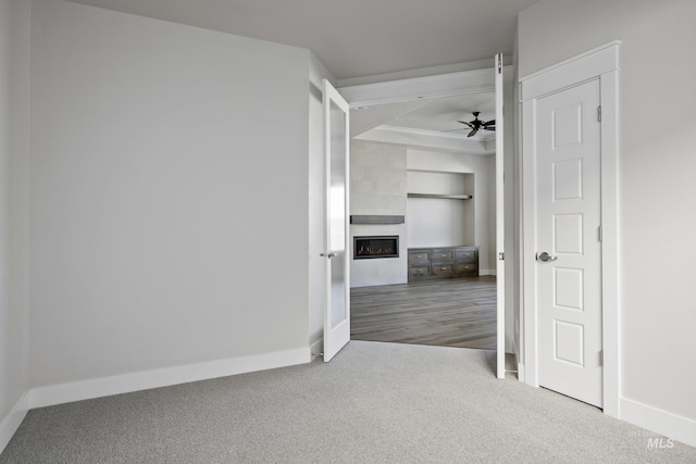 interior space with a fireplace, baseboards, carpet, and a ceiling fan