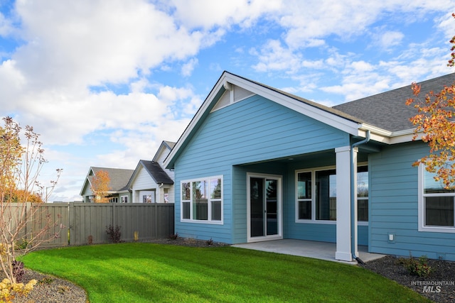 back of property with fence, a lawn, and a patio area