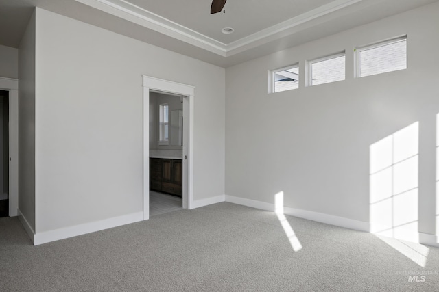 unfurnished room with crown molding, carpet, ceiling fan, a raised ceiling, and baseboards