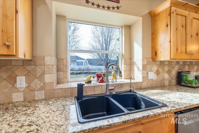 kitchen featuring a sink, light stone countertops, backsplash, and dishwasher