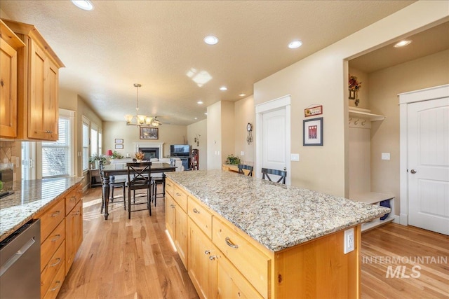 kitchen featuring recessed lighting, a kitchen island, light wood-style floors, and stainless steel dishwasher