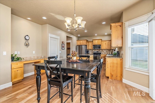 dining room with a notable chandelier, a textured ceiling, built in desk, light wood finished floors, and baseboards