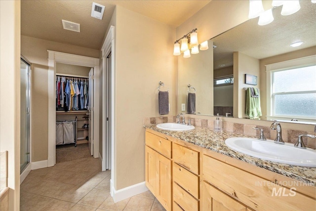 bathroom featuring tile patterned flooring, double vanity, visible vents, and a sink