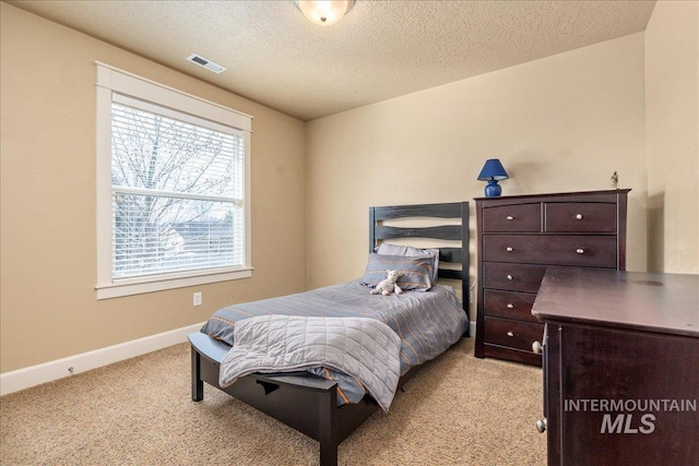 bedroom with a textured ceiling, baseboards, visible vents, and light carpet