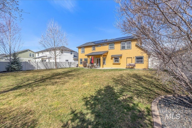 rear view of property featuring solar panels, a patio, a lawn, and a fenced backyard