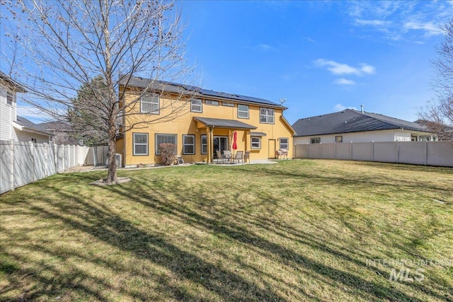 back of house featuring a patio area, solar panels, a lawn, and a fenced backyard