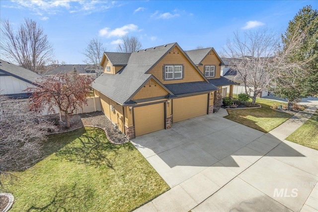 view of front of home featuring driveway, a front lawn, stone siding, fence, and an attached garage