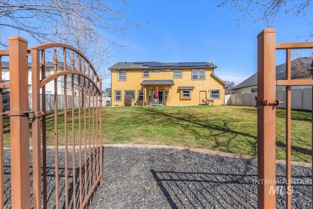 view of front of property with roof mounted solar panels, fence private yard, and a front lawn